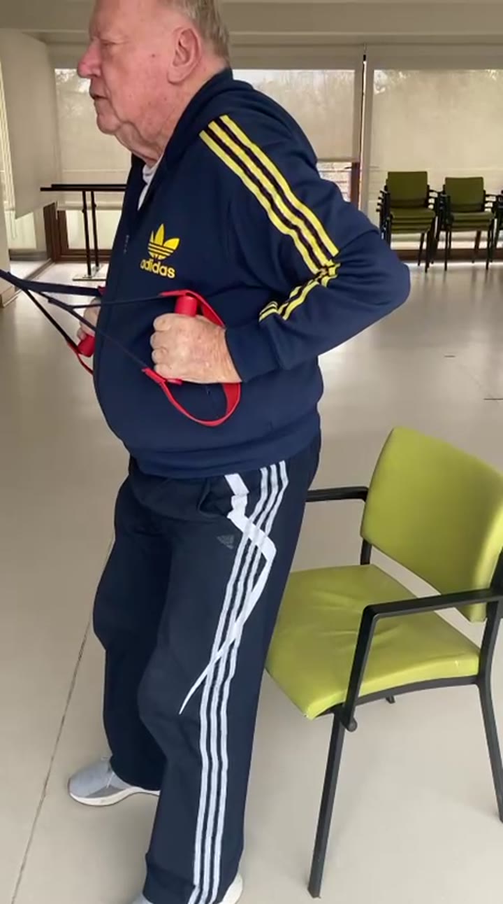 Fuerza de brazos con banda durante una sesión de rehabilitación para adultos mayores